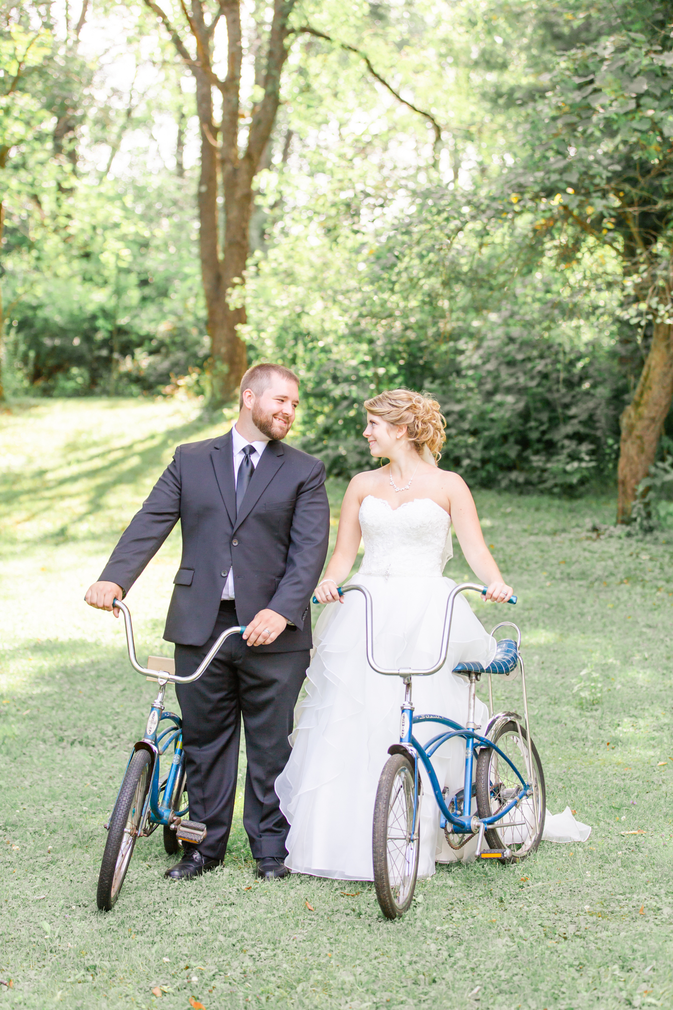 bride and groom pose with old-fashioned bikes
